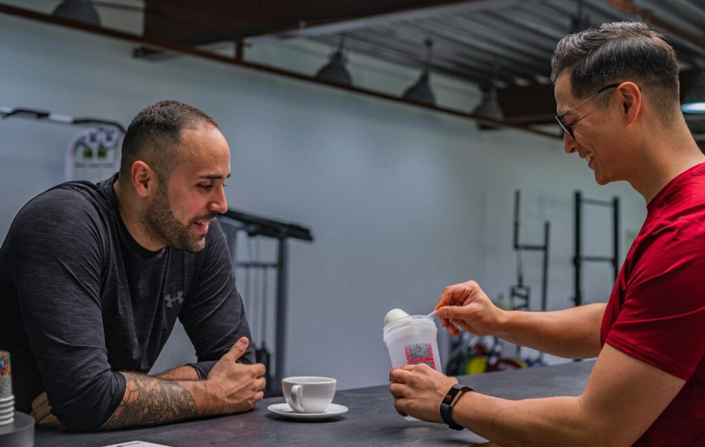 proteínas HSN. Aparecen dos hombres con un batido de proteínas en la mano.