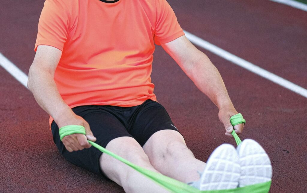 bandas elásticas. Aparece un hombre entrenando en una pista de atletismo.